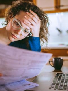Woman looking at bill with hand on forehead